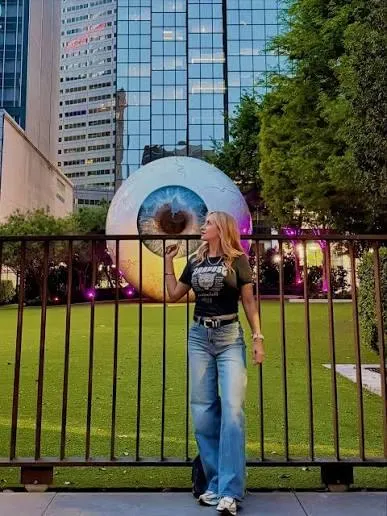 Turista posando com a escultura do olho gigante em Downtown Dallas