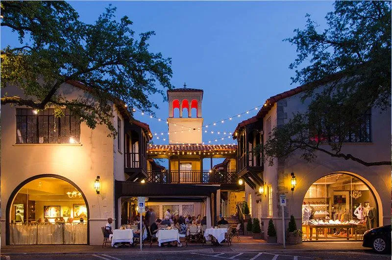 Highland Park Village iluminado ao anoitecer, com restaurantes de arquitetura espanhola