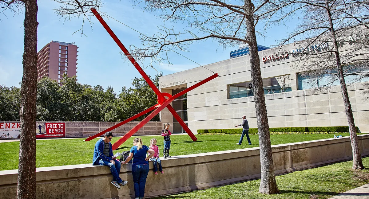 Família no gramado do Dallas Museum of Art, ao lado de uma grande escultura vermelha