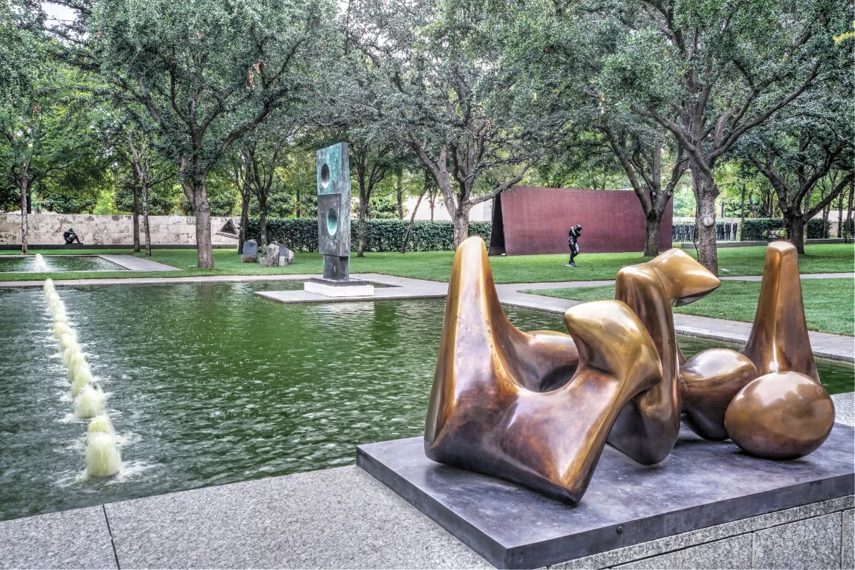 Jardim do Nasher Sculpture Center com espelho d’água, árvores e esculturas de bronze