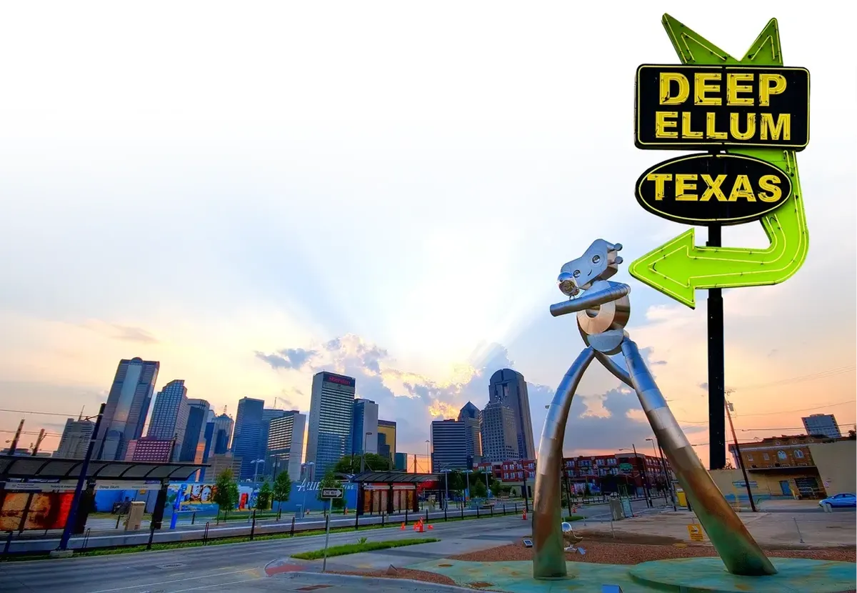 Placa neon de Deep Ellum e a escultura Traveling Man, com o skyline de Dallas ao fundo