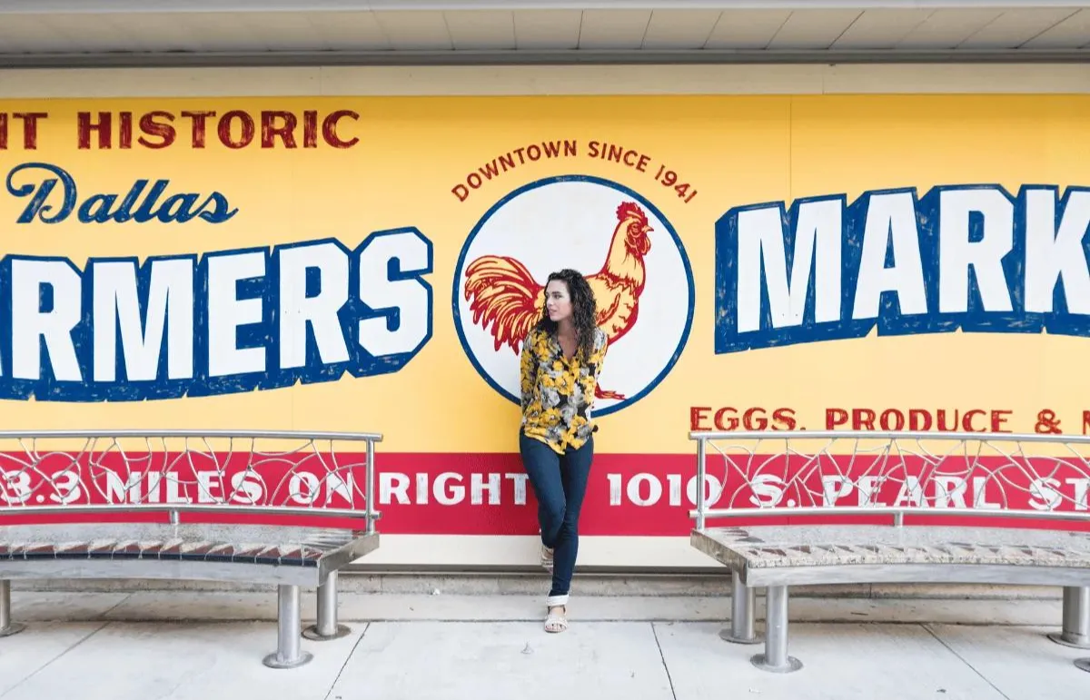 Turista posando em frente ao mural do Dallas Farmers Market