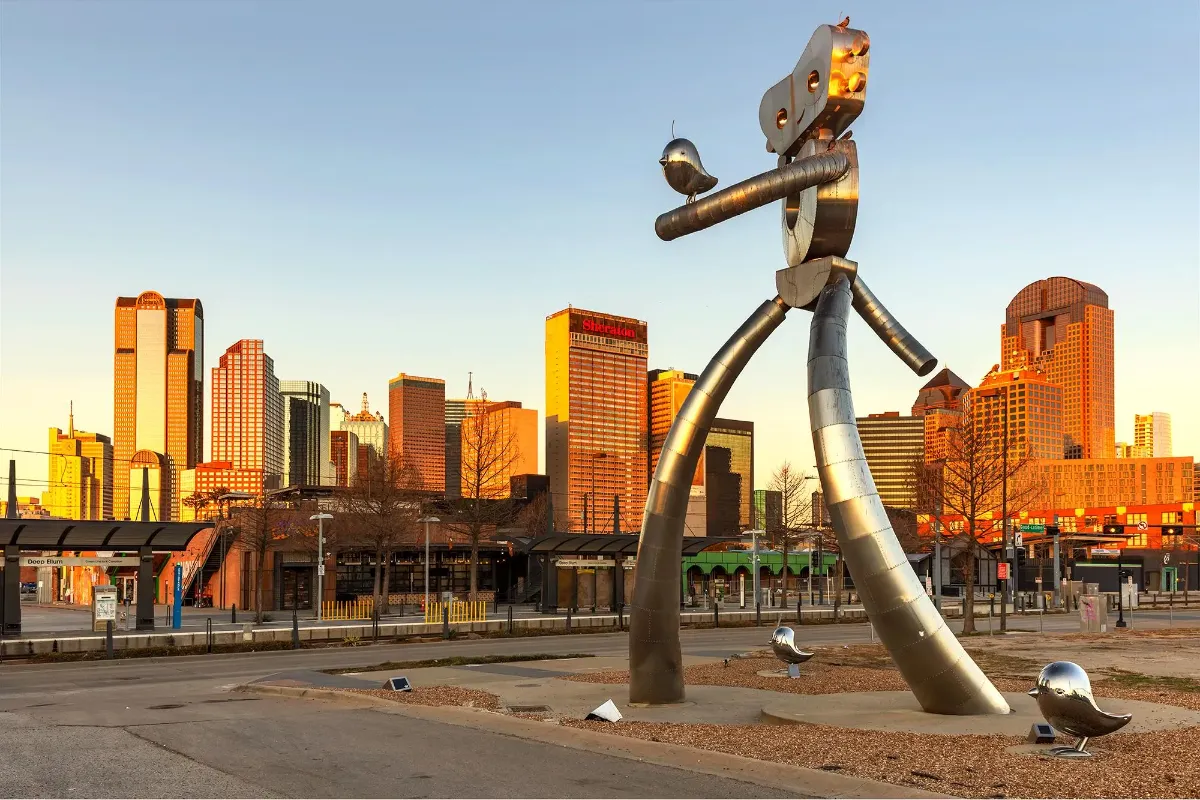 Escultura do robô viajante em Deep Ellum com o skyline de Dallas ao fundo no fim de tarde