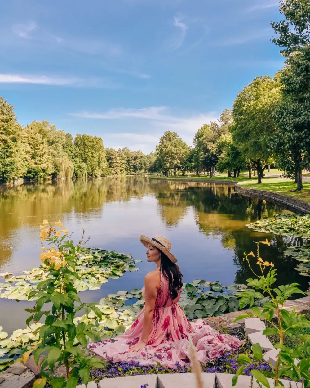 Mulher de chapéu de palha à beira de um lago com vitórias-régias em Dallas