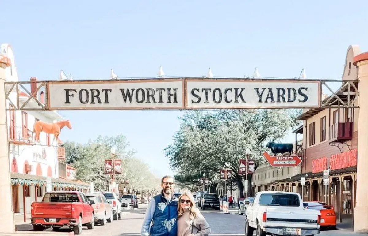 Casal de turistas sob a placa Fort Worth Stock Yards