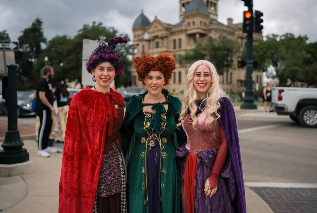 Três visitantes fantasiadas de bruxas no centro de Denton durante o Halloween