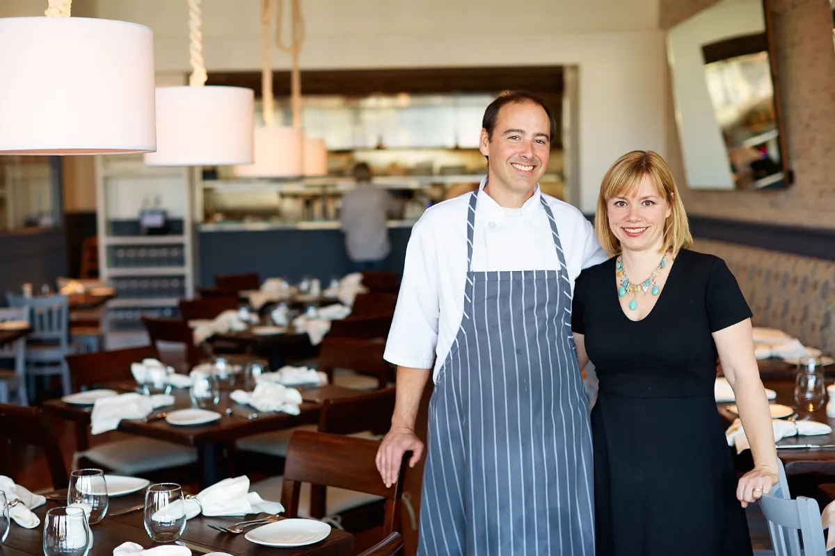 Chef e sócia do Gemma no salão do restaurante, com as mesas postas