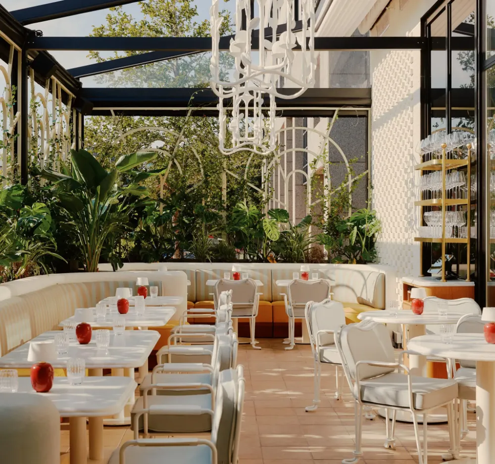 Terraço do Mamani com mesas brancas, plantas tropicais e lustre escultural