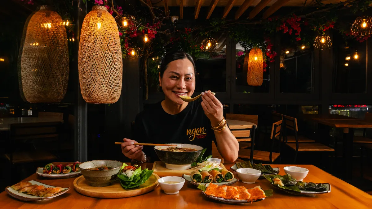 Mesa do Ngon Vietnamese Kitchen com sopa, rolinhos e pratos vietnamitas sob luminárias de palha