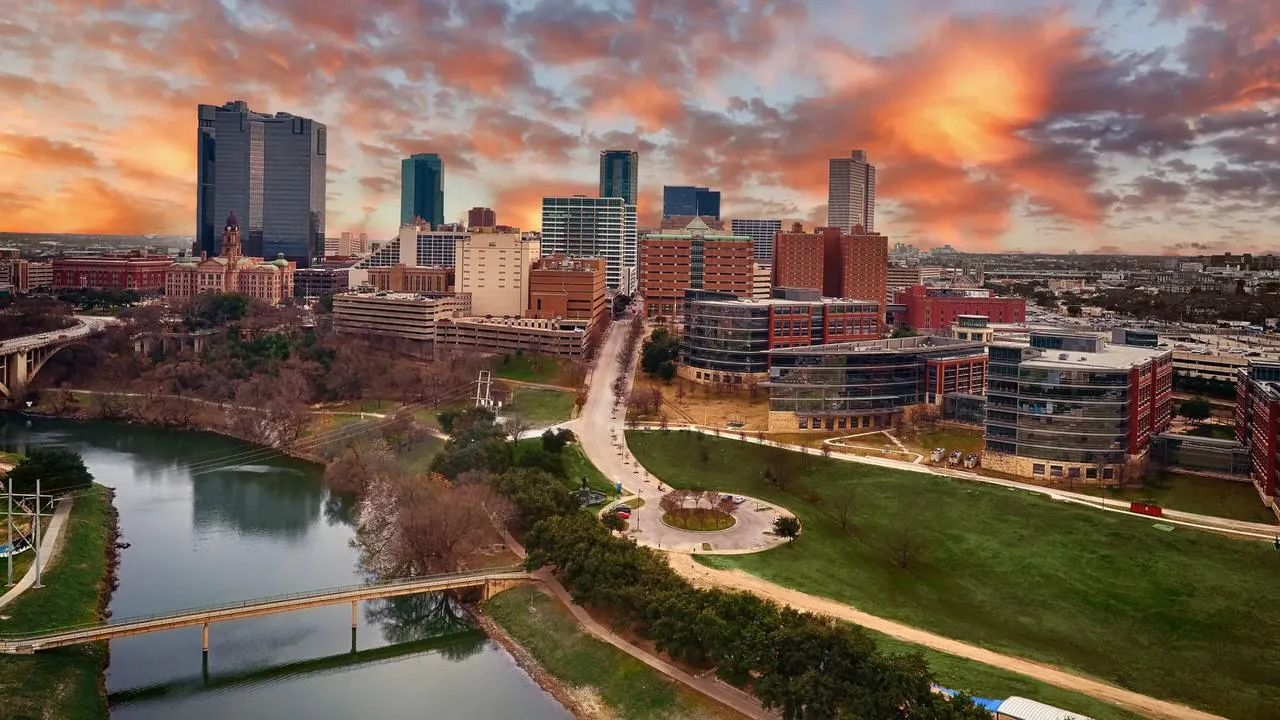 Vista aérea de Fort Worth ao pôr do sol, com o Trinity River e o centro da cidade