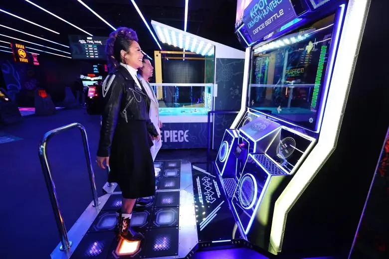 Visitante jogando em uma máquina de fliperama neon na Netflix House