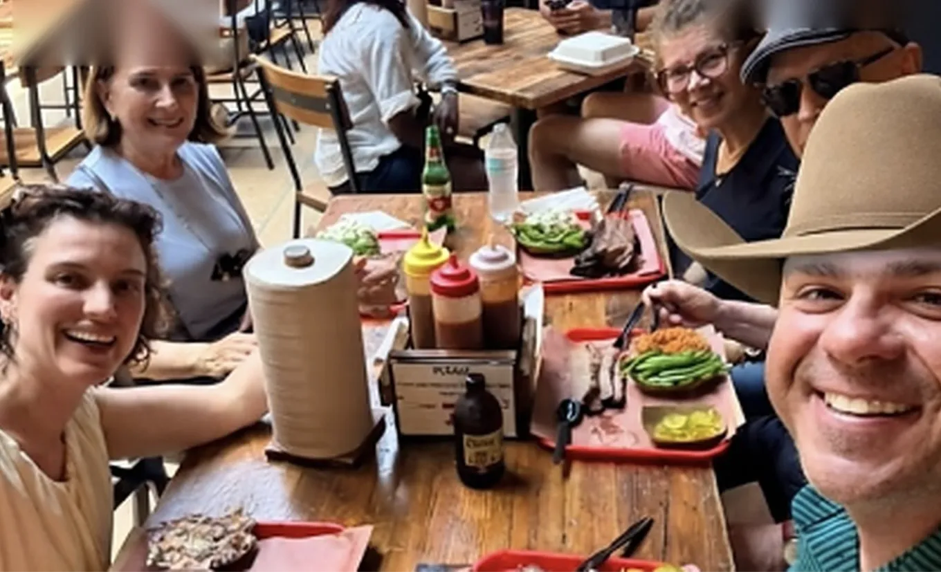 Turistas brasileiros com o Guia Dallas comendo churrasco texano em uma mesa de BBQ