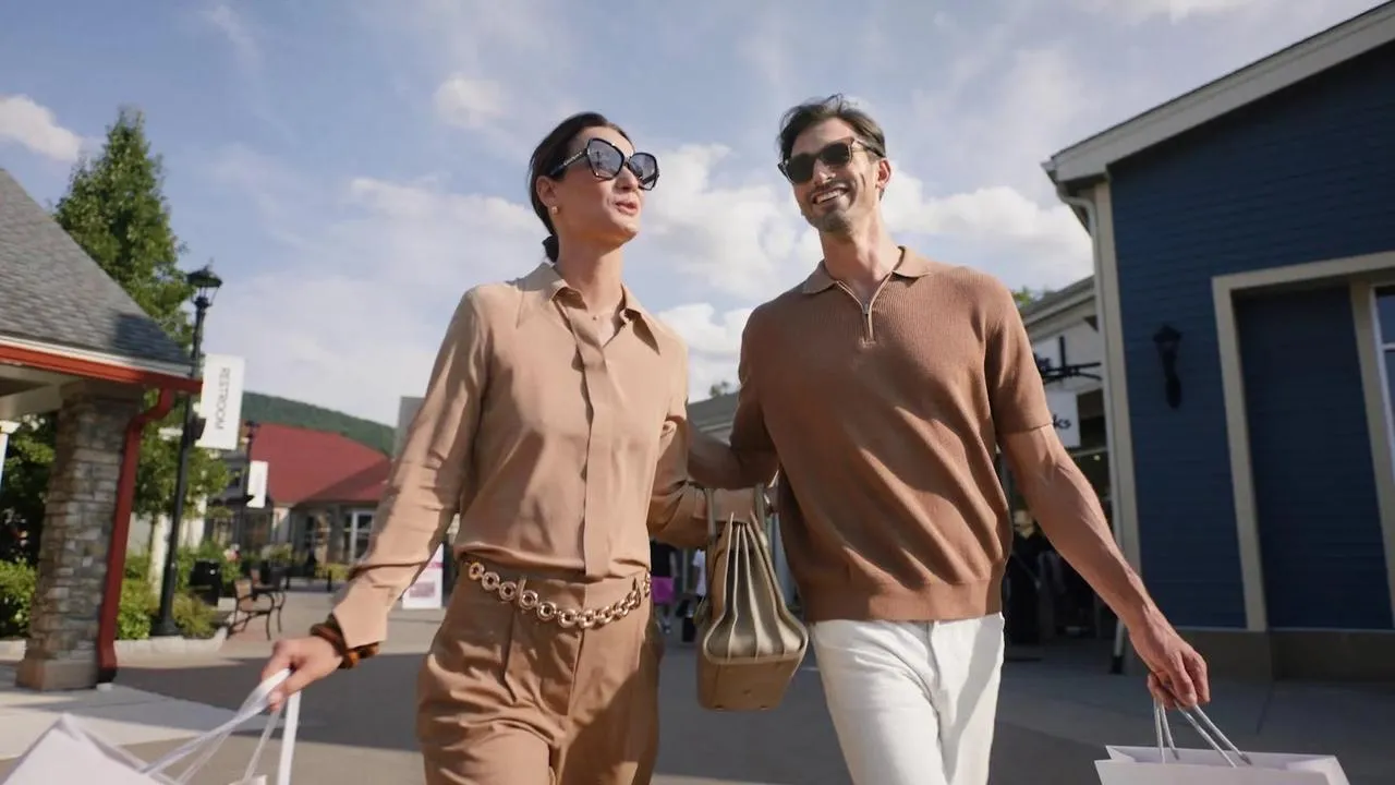 Casal caminhando com sacolas no Allen Premium Outlets