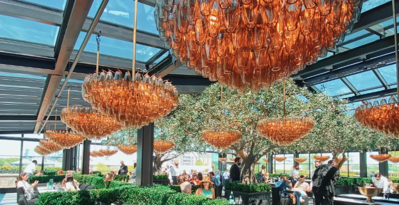 Salão do RH Rooftop Restaurant em Dallas, com lustres de cristal, oliveiras e teto de vidro